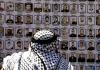 مواطن فلسطيني يُطالع لوحة للأسرى القدامى