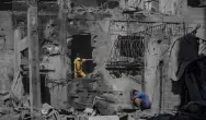 فلسطينيون وسط أنقاض مبان مدمرة