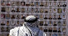 مواطن فلسطيني يُطالع لوحة للأسرى القدامى