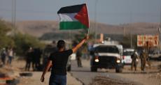شاب يرفع علم فلسطين خلال مواجهات في الضفة.jpg