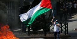 شاب يرفع علم فلسطين خلال مواجهات مع الاحتلال بالضفة.jpeg