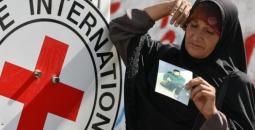 سيدة فلسطينية تحمل صورة نجلها الأسير بجانب شعار الصليب الأحمر.jpg