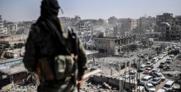 مقاتل في سورية يقف على أنقاض مبانٍ تعرضت للقصف.jpg
