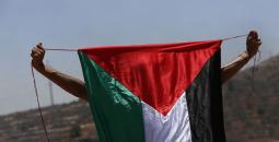 شاب فلسطيني يرفع علم فلسطين خلال المواجهات.jpg