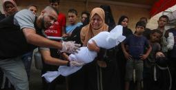 فلسطينية تشيع طفلها الذي استشهد بمجزرة في غزة.jpg