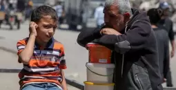 فلسطيني وطفله خلال انتظار مساعدات في غزة.webp