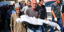 فلسطيني يحمل طفله بعد استشهاده في مجزرة بغزة.webp