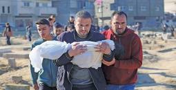 فلسطيني يحمل طفله عقب استشهاده بمجزرة إسرائيلية.jpg
