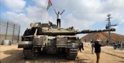 فلسطيني يرفع علامة النصر وعلم فلسطين فوق ميركافاة إسرائيلية.jpeg