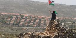 فلسطيني يرفع علم فلسطين مقابل مستوطنة في رام الله