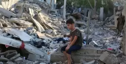 طفل فلسطيني يجلس على ركام منزل عائلته في غزة.webp