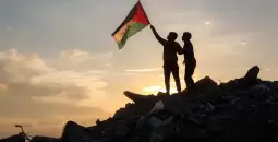 فلسطينيان يرفعان علم فلسطين بغزة.webp