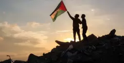 طفلان يرفعان علم فلسطين على منازل مدمرة في غزة.webp