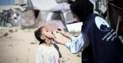 موظفة أممية تقوم بـ تطعيم طفلة في غزة.jpg
