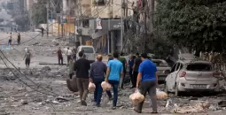 مواطنون يحملون أكياس خبز بين الدمار في غزة.webp