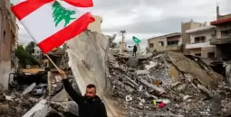 مواطن لبناني يرفع علم بلاده على أنقاض منازل دمرها الاحتلال.webp