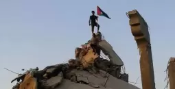 شاب يرفع علم فلسطين على منزل مدمر في غزة.webp