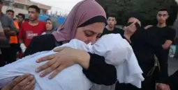 سيدة فلسطينية تودع طفلها الشهيد في غزة