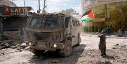 مسن يرفع علم فلسطين قرب آلية عسكرية إسرائيلية.jpg
