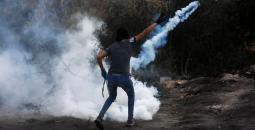 شاب فلسطيني يعيد قنبلة غاز باتجاه قوات الاحتلال.jpg