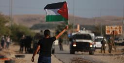 شاب يرفع علم فلسطين خلال مواجهات في الضفة.jpg