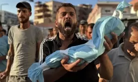 مواطن يحمل جنين قتله الاحتلال في غزة