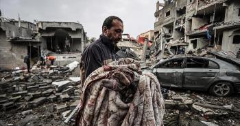 فلسطيني يحمل طفلته بعد مجزرة في غزة.jpg