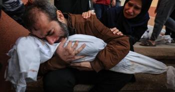 فلسطيني يودع طفلته التي استشهدت بمجزرة إسرائيلية في غزة.jpg
