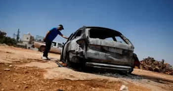 فلسطيني يتفقد سيارة محترقة بعد هجوم شنه مستوطنون على قرية كفر مالك.webp