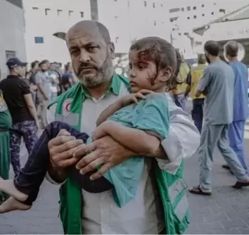 مسعف يحمل طفلة مصابة.webp