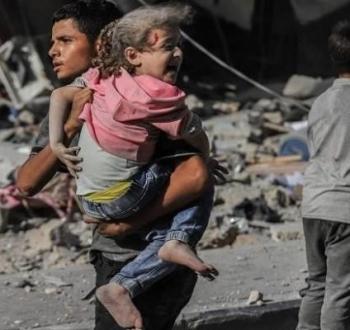 صورة أرشيفية لمواطن ينقل طفلة مصابة من مجزرة في بيت لاهيا.jpg