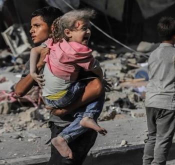 صورة أرشيفية لشاب يبتعد رفقة شقيقته الطفلة عن مكان قصف في غزة