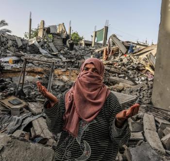 مواطنة فلسطينية تقف أمام مربع سكني بعد أن دمرته طائرات الاحتلال في قطاع غزة