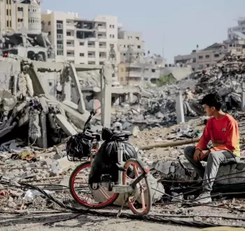 فتى فلسطيني يجلس قرب منزل عائلته المدمر في غزة.webp