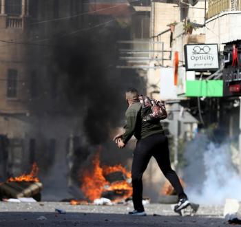 شاب فلسطيني يلقي الحجارة خلال مواجهات في الضفة الغربية.jpg