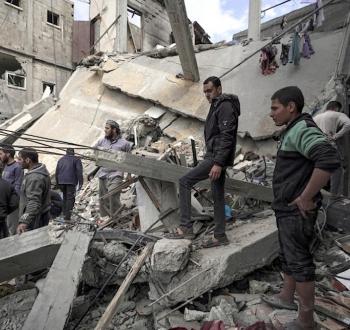 فلسطينيون على أنقاض مبنى دمره الاحتلال الإسرائيلي في قطاع غزة.jpg