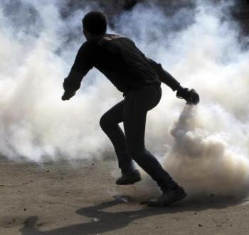 شاب فلسطيني يلقي قنبلة غاز على جنود الاحتلال.jpg