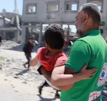 مسعف فلسطيني ينقل طفلًا من مكان مجزرة في غزة
