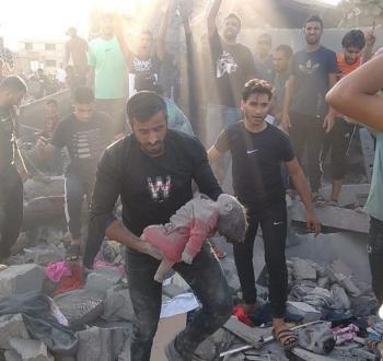 فلسطيني ينتشل جثمان طفلة من مكان قصف إسرائيلي في غزة.jpg