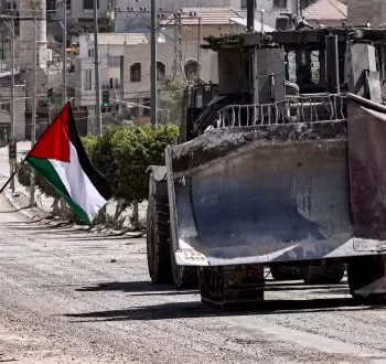 فلسطيني يقف بالقرب من جرافة إسرائيلية في طولكرم.webp