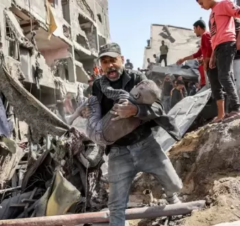 فلسطيني يحمل طفله المصاب عقب قصف إسرائيلي شمال قطاع غزة