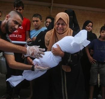 فلسطينية تشيع طفلها الذي استشهد بمجزرة في غزة.jpg