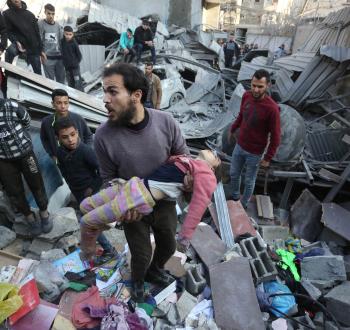 مواطن يحمل طفلته عقب مجزرة إسرائيلية في غزة.jpg
