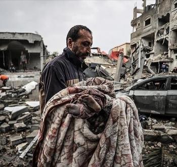 فلسطيني يحمل طفلته بعد استشهادها في مجزرة إسرائيلية بغزة.jpg