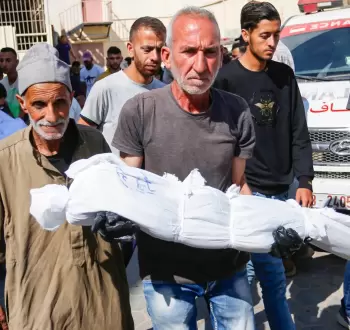 فلسطيني يحمل طفله بعد استشهاده في مجزرة بغزة.webp