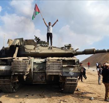 فلسطيني يرفع علامة النصر وعلم فلسطين فوق ميركافاة إسرائيلية.jpeg