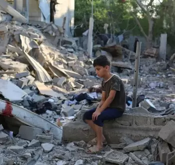 طفل فلسطيني يجلس على ركام منزل عائلته في غزة.webp