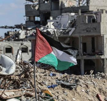رفع علم فلسطين قرب منازل مدمرة في غزة.jpg