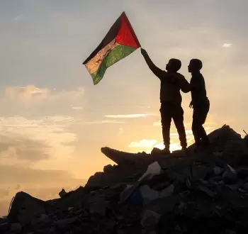 فلسطينيان يرفعان علم فلسطين بغزة.webp