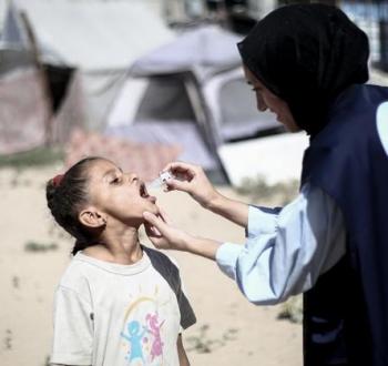 موظفة أممية تقوم بـ تطعيم طفلة في غزة.jpg